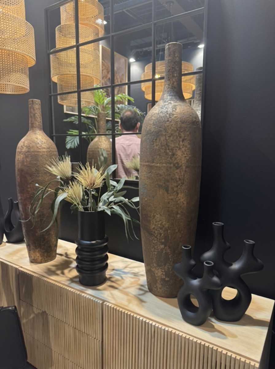 Samling vaser i mörka och gyllene toner på ett sideboard, med en svart vas och blommor