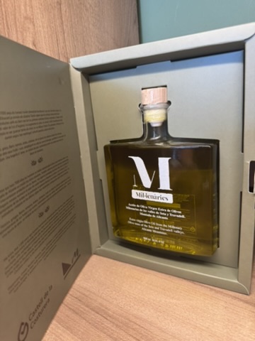 Flaska olivolja i en öppnad presentförpackning med kork och texten Mil·lenàries